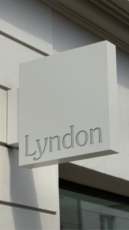 An example of a projecting sign above the Lyndon showroom. The sign is square, light grey in colour and has the Lyndon positioned at the bottom.